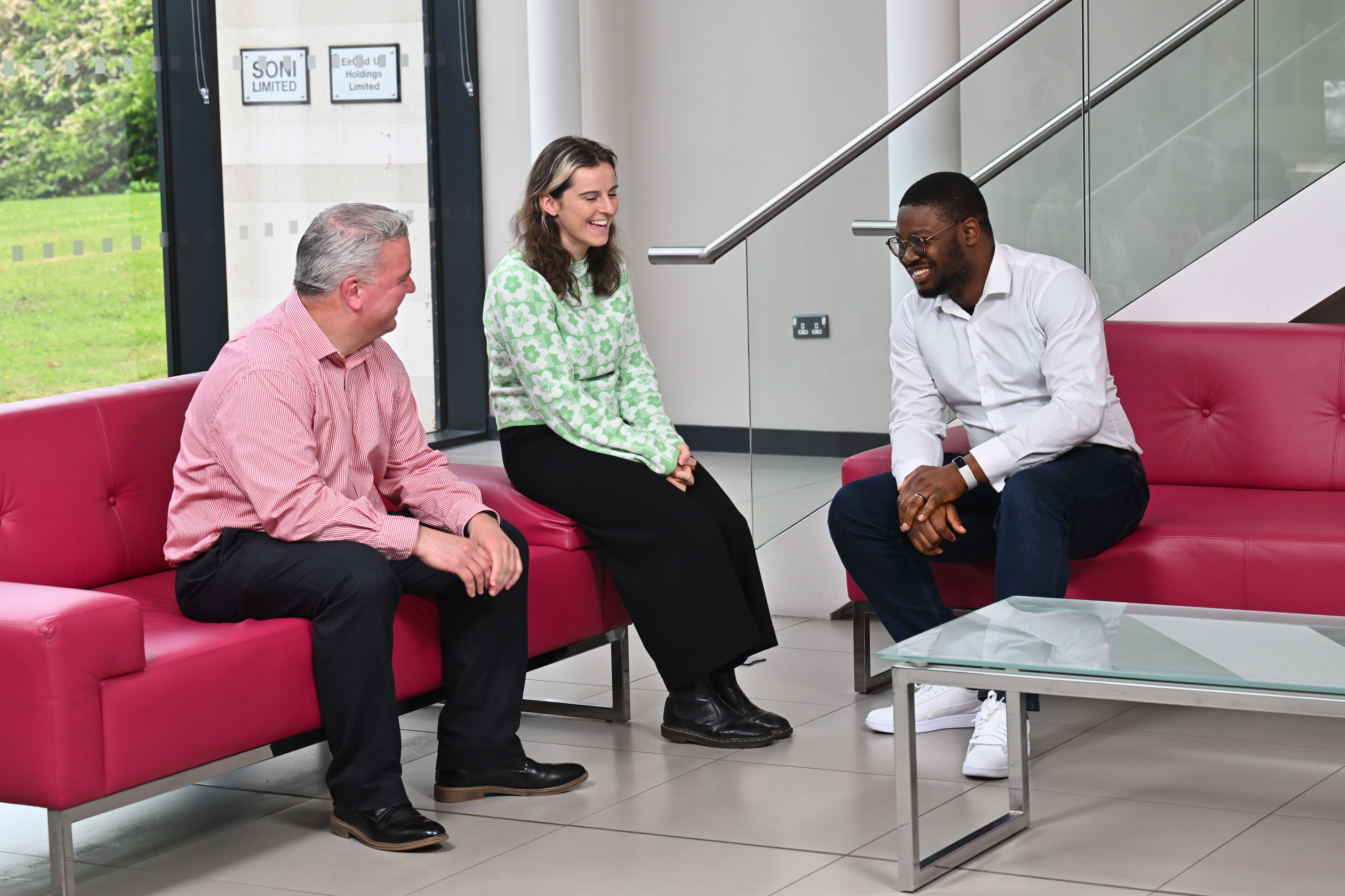 Three people sitting and talking in an office lobby